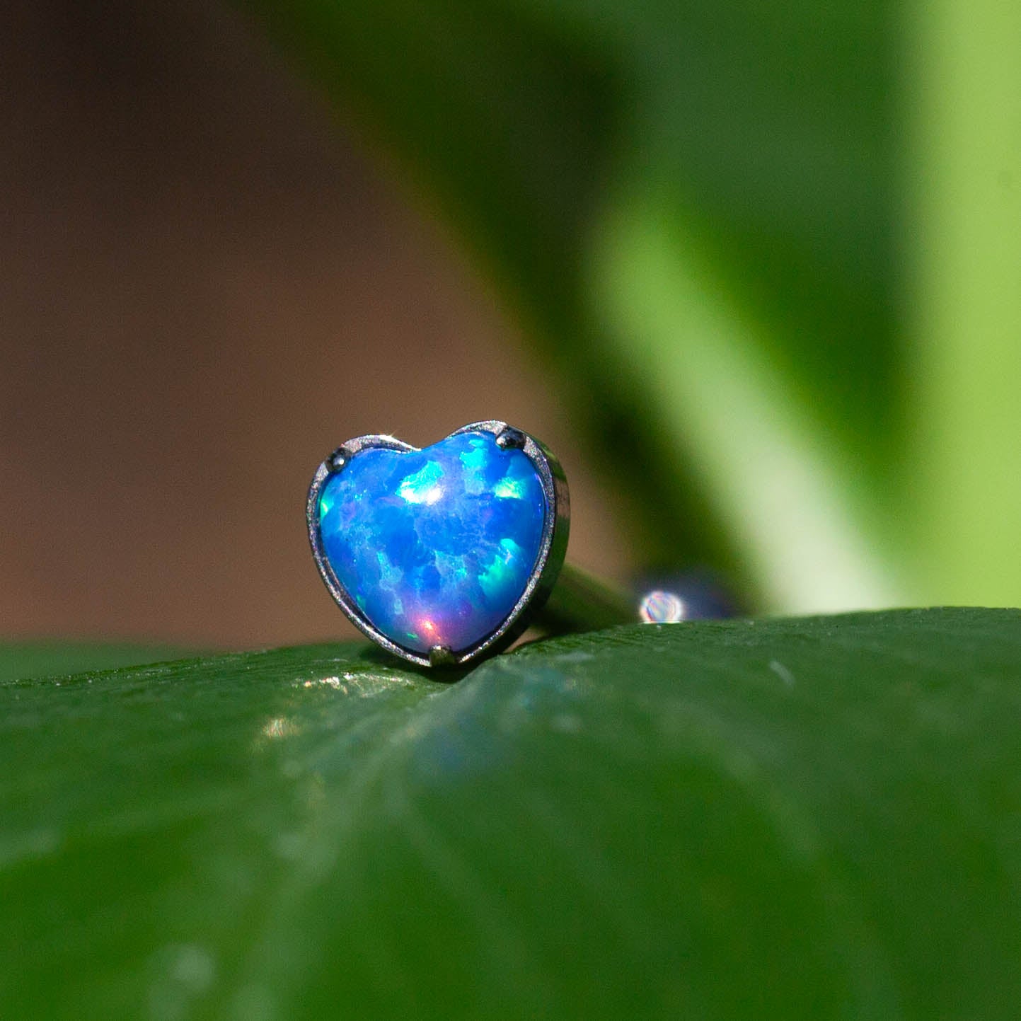 Cuore con opale sintetico, su base in titanio ASTM F136 da implantologia certificato. L'opale sintetico riproduce fedelmente i colori più vivaci e luminosi che esistono in natura.&nbsp; Si tratta di un colore puro che non sbiadisce col tempo. Come l'opale naturale, la struttura interna genera una diffrazione della luce, che porta ad un colore forte e lo rende davvero versatile. Consigliato per chi ama abbinamenti particolari.